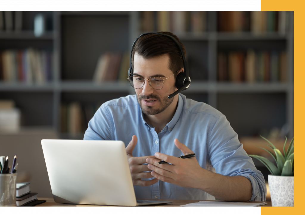 man with headset talking into a laptop