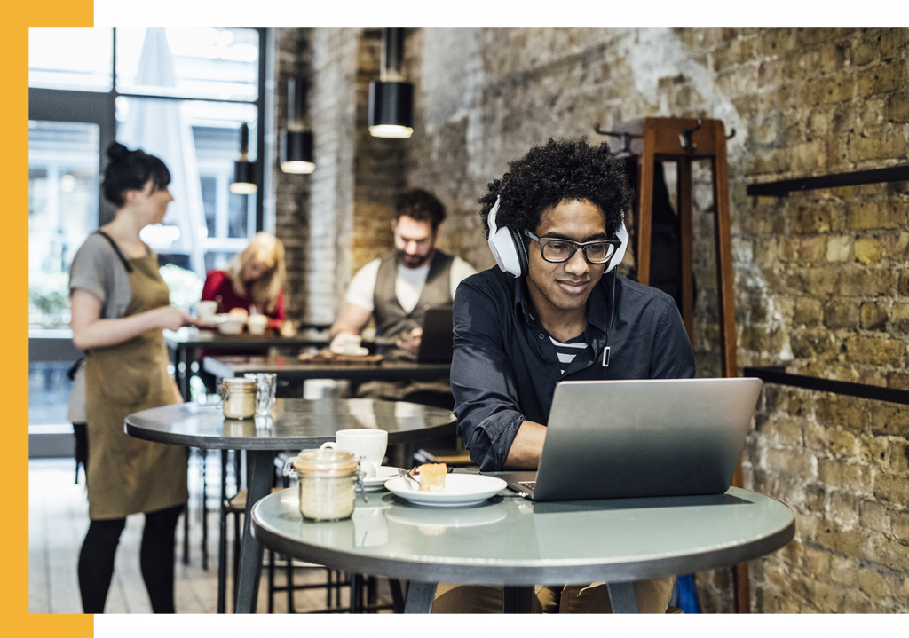 man in coffee shop using laptop with headphone